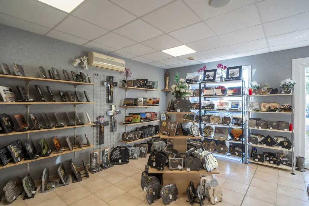 Boutique d'articles funéraires exposant des plaques en granit, croix et monuments sur des étagères